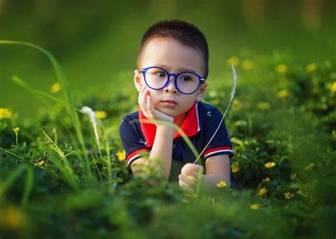 Vaikas su akiniais skaito knygą