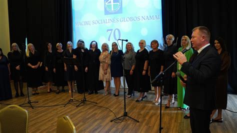 Grupė senjorų, bendraujančių lauke prie socialinės globos namų