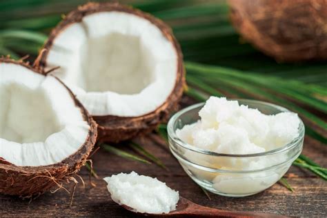 Kokoso aliejaus buteliukas ir vaisius, simbolizuojantys natūralumą.