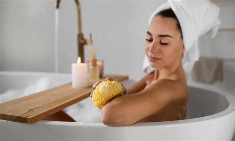 Moteris atsipalaiduoja vonioje su rankšluosčiu po galva