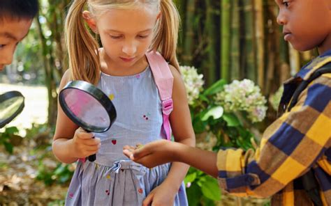 Vaikai, tyrinėjantys gamtą su padidinimo stiklu