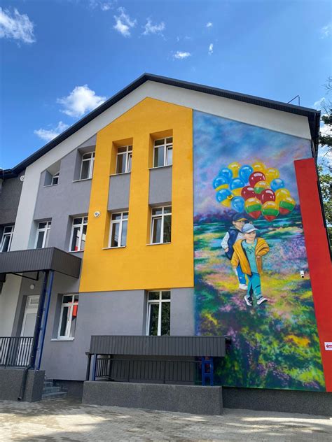 Vaizdas, vaizduojantis vaikų darželio fasadą ir žalią aplinką