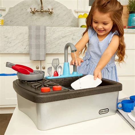 vaikas žaidžia su vandeniu ir indais