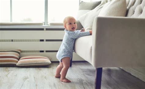 Kūdikis stovi įsikibęs į baldą