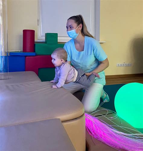 Kūdikis atlieka pratimus su kineziterapeutu